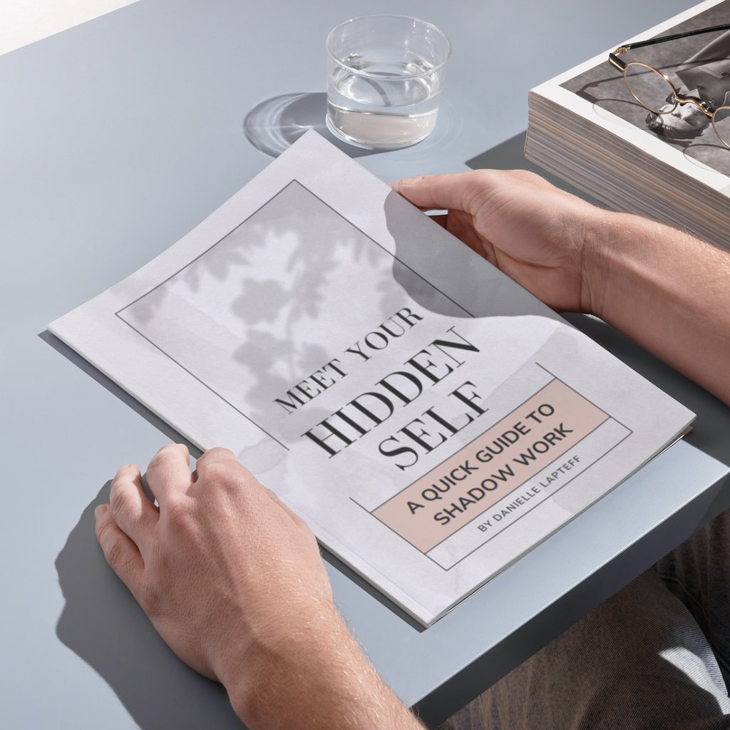 hands holding a workbook on a table with a drink. Title Meet Your Hidden Self