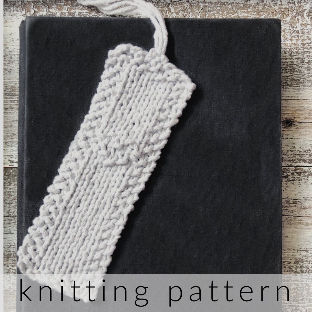 White knit bookmark with heart detail on black book.