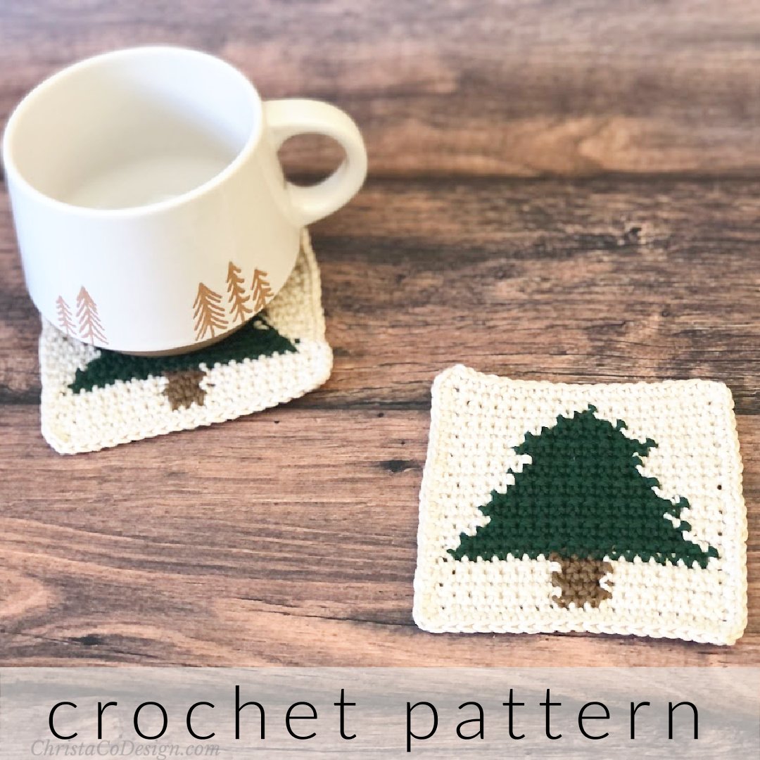 Two crochet coaster with christmas trees on table with mug on one.