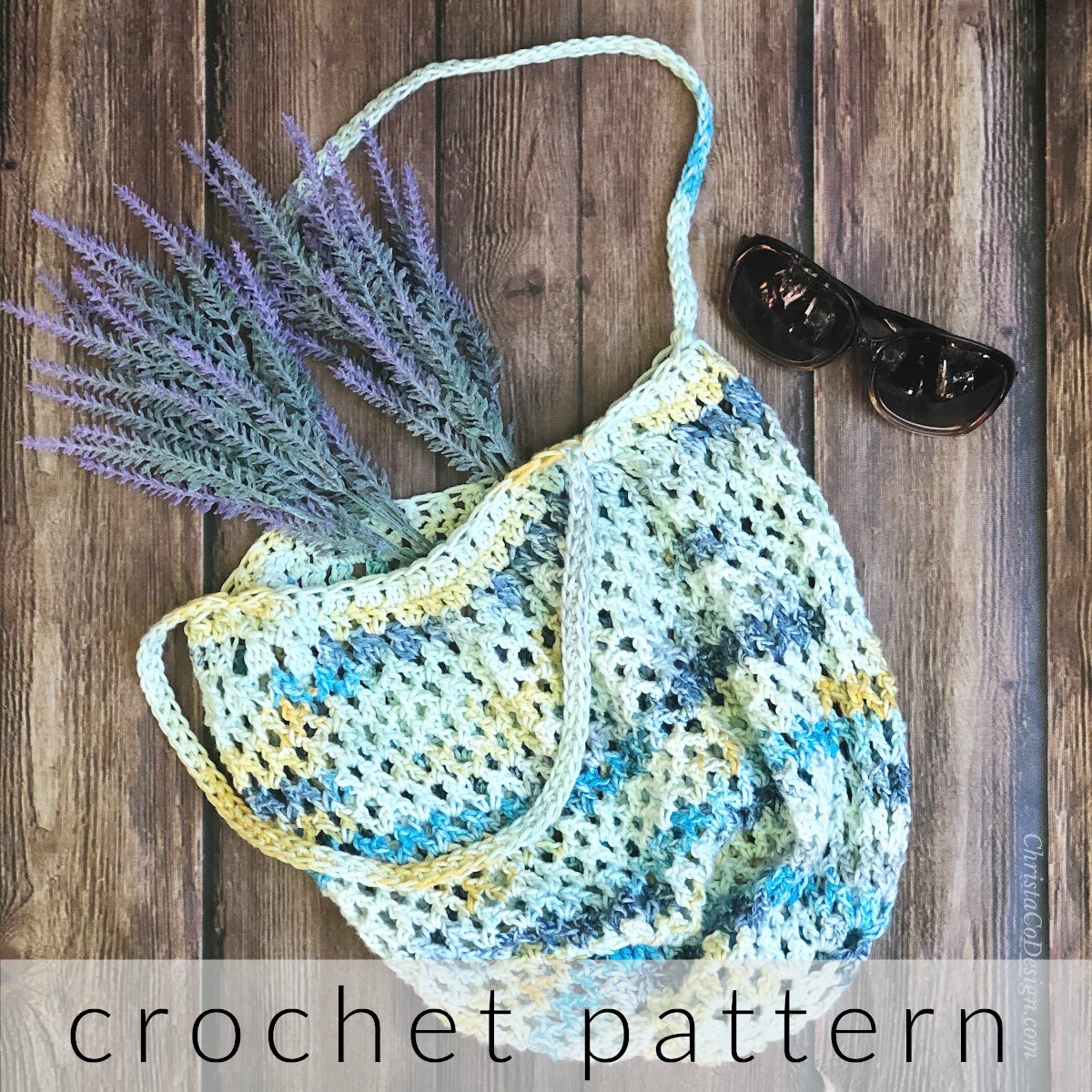 Crochet bag with lavender and sunglasses on table.