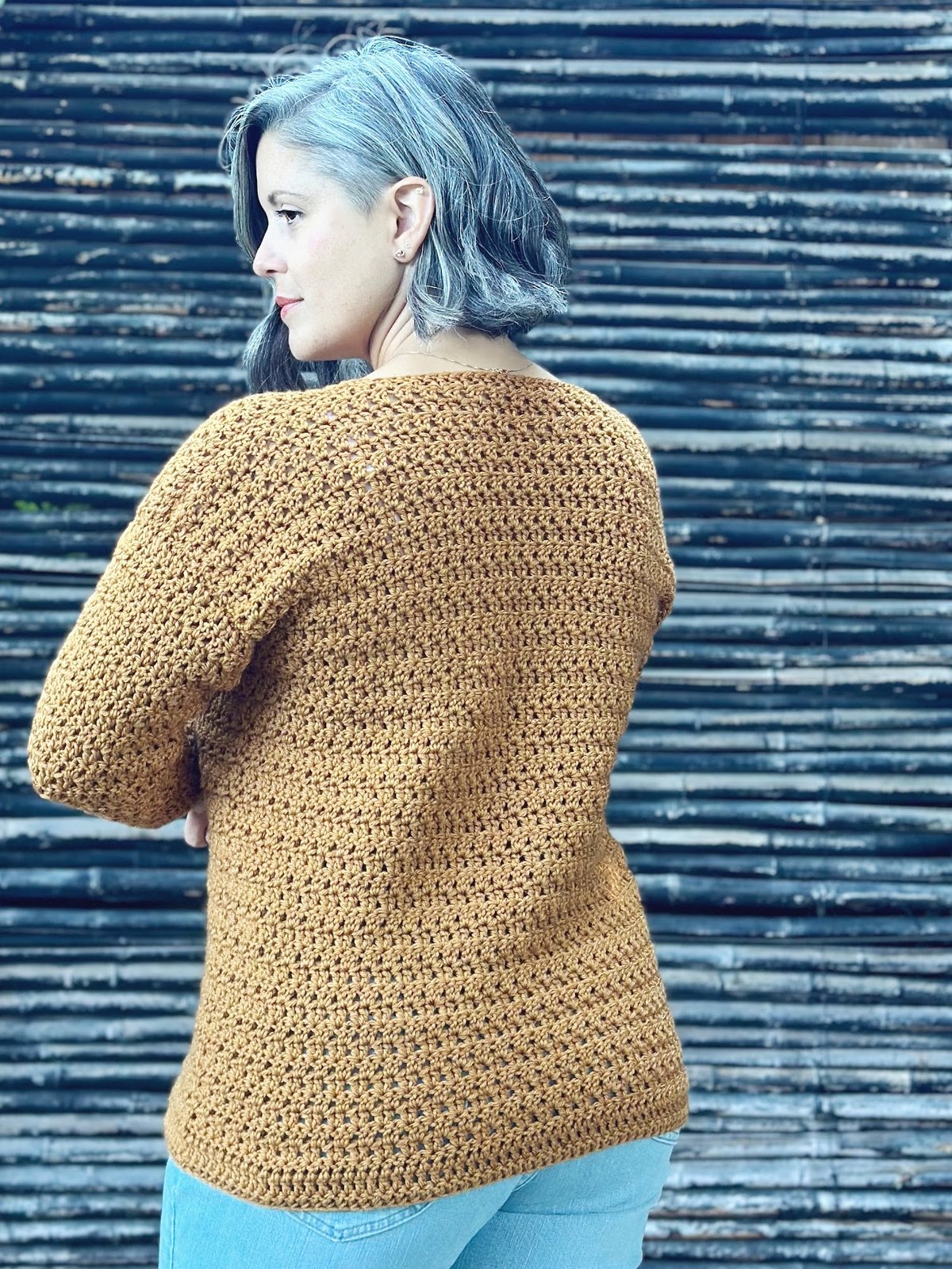 Woman turned to show back of crochet sweater.