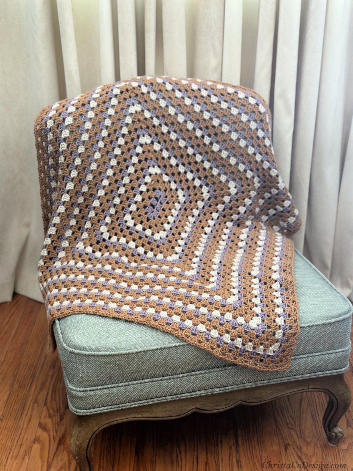 Brown, purple and white granny rectangle blanket draped to show center.