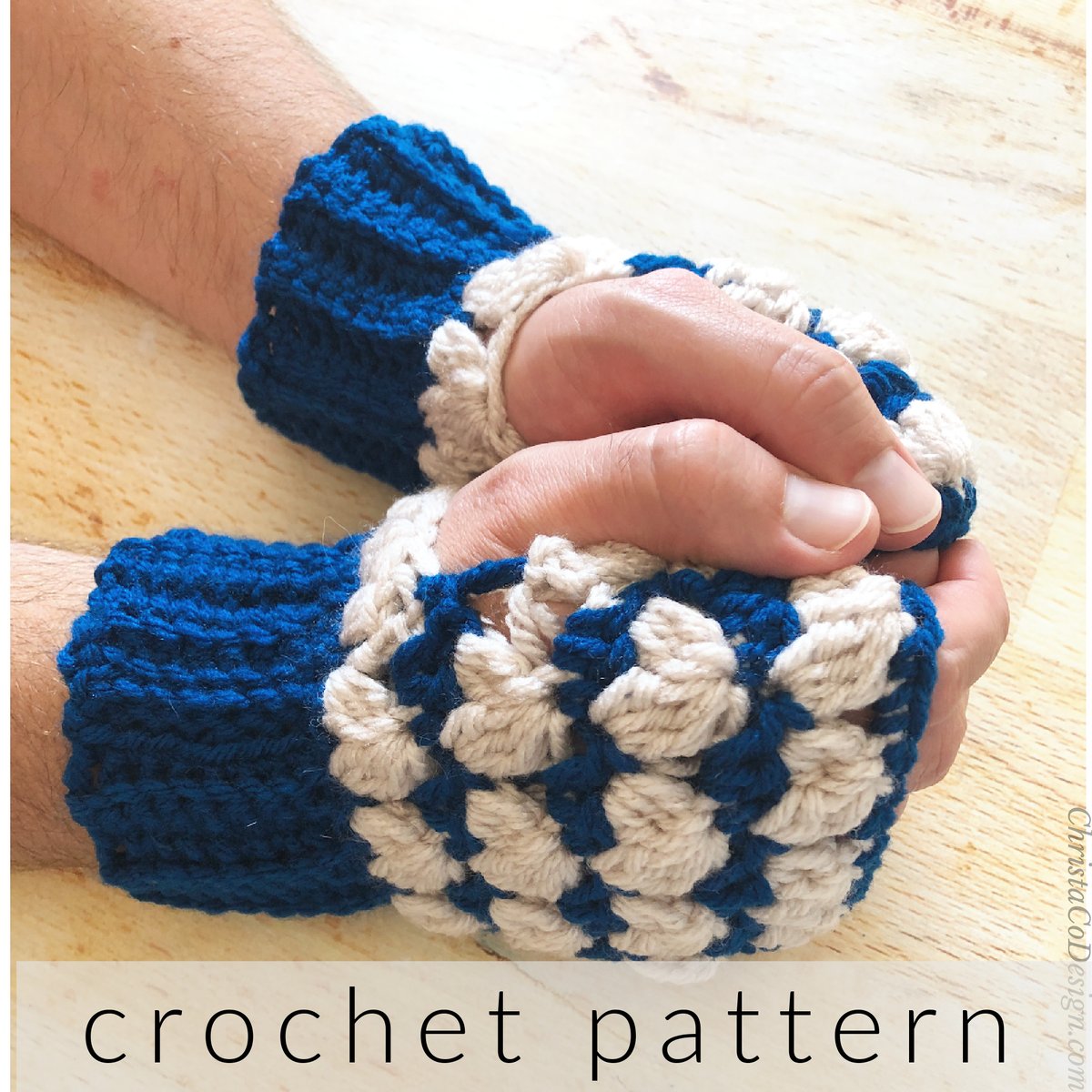 Mens hands in blue and white crochet fingerless gloves on table.