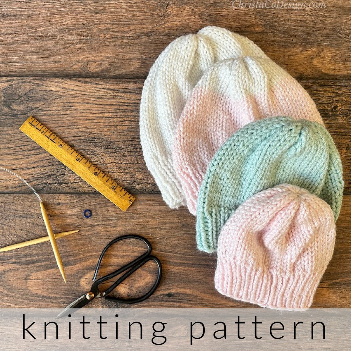 4 knit hats in white blue and pink next to knitting notions.