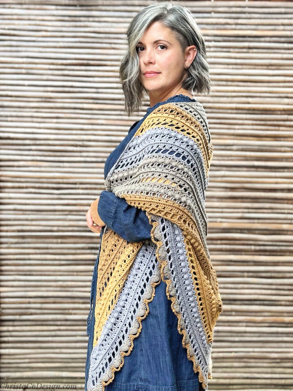 Side view of woman in delicate crochet shawl of grey and golden brown.