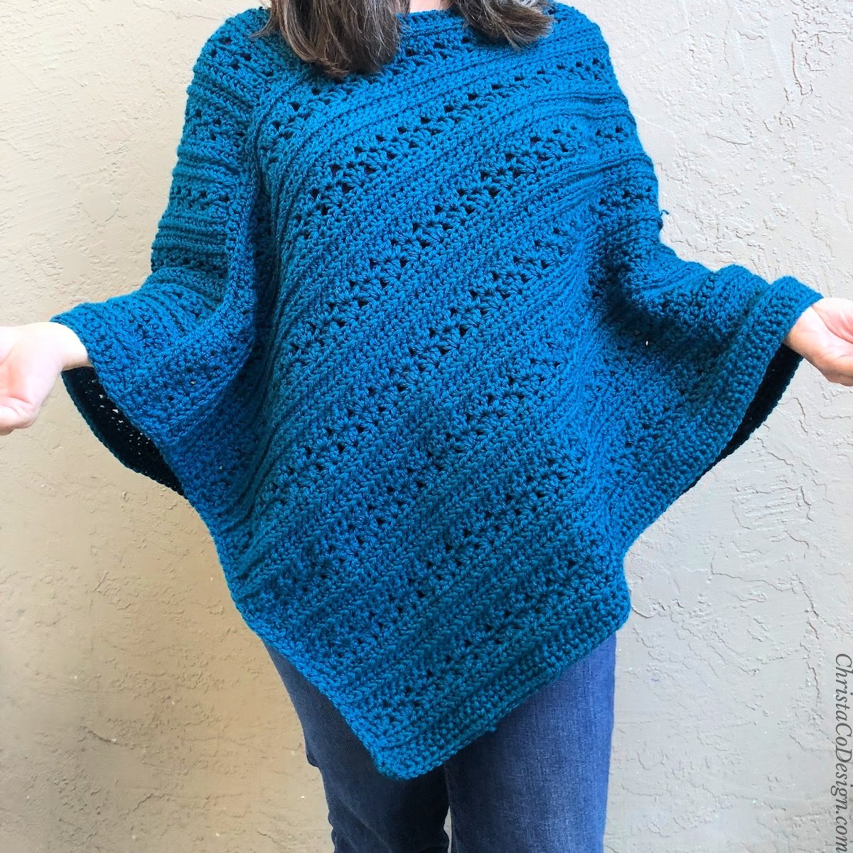 Woman wearing textured blue crochet poncho.
