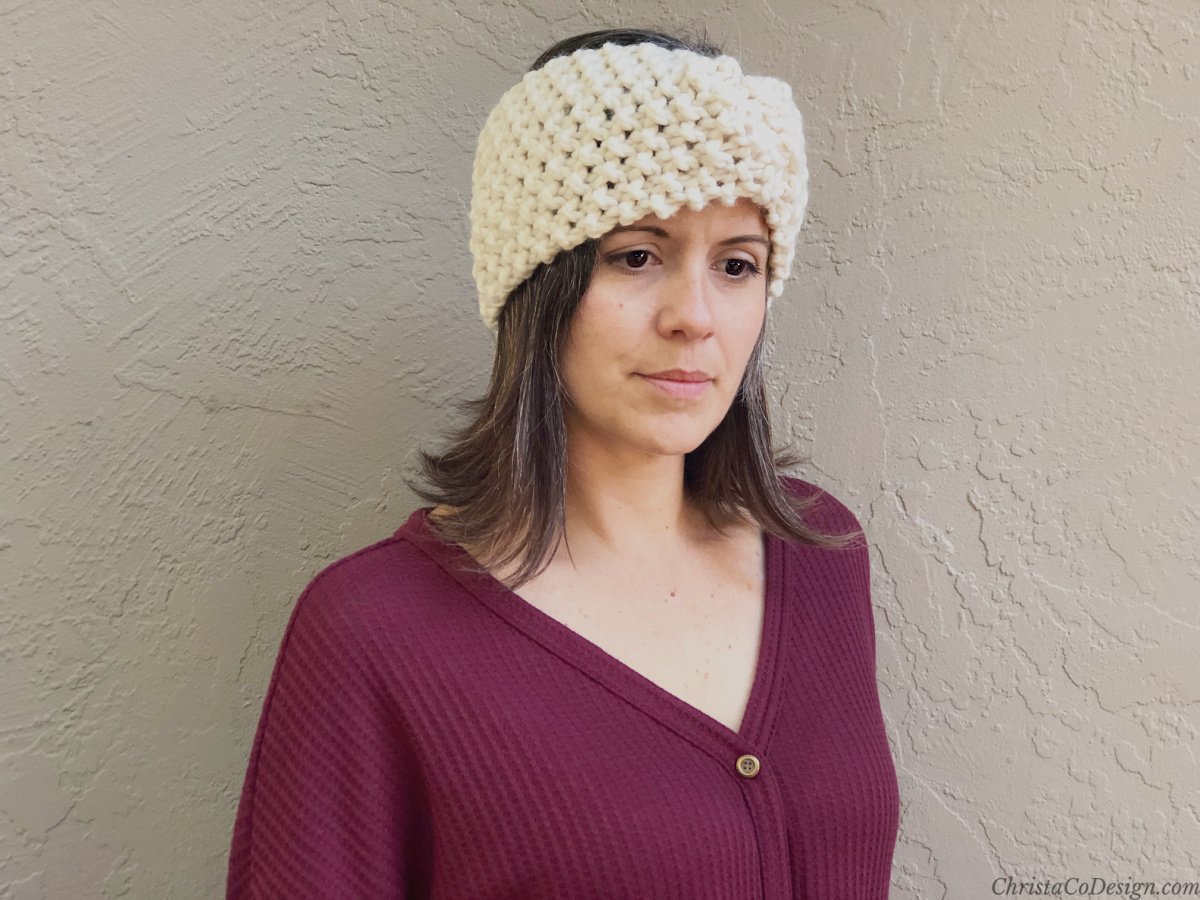Woman looking down in chunky knit earwarmer.