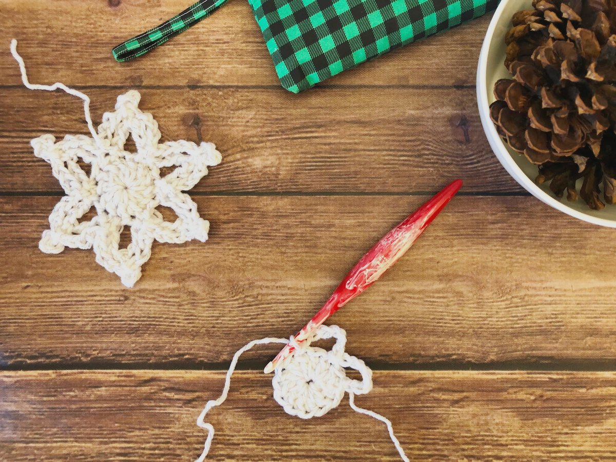 Crochet snowflake in progress on hook.