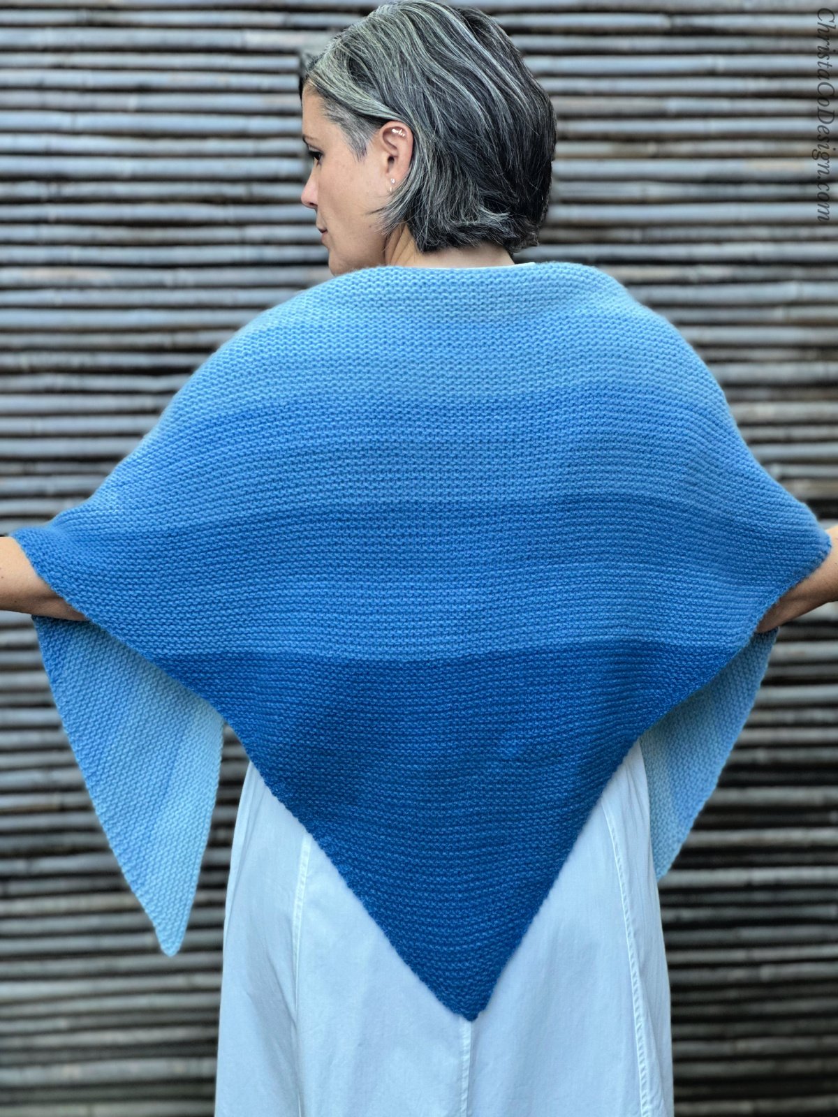 Woman with blue ombre knit shawl draped over back.