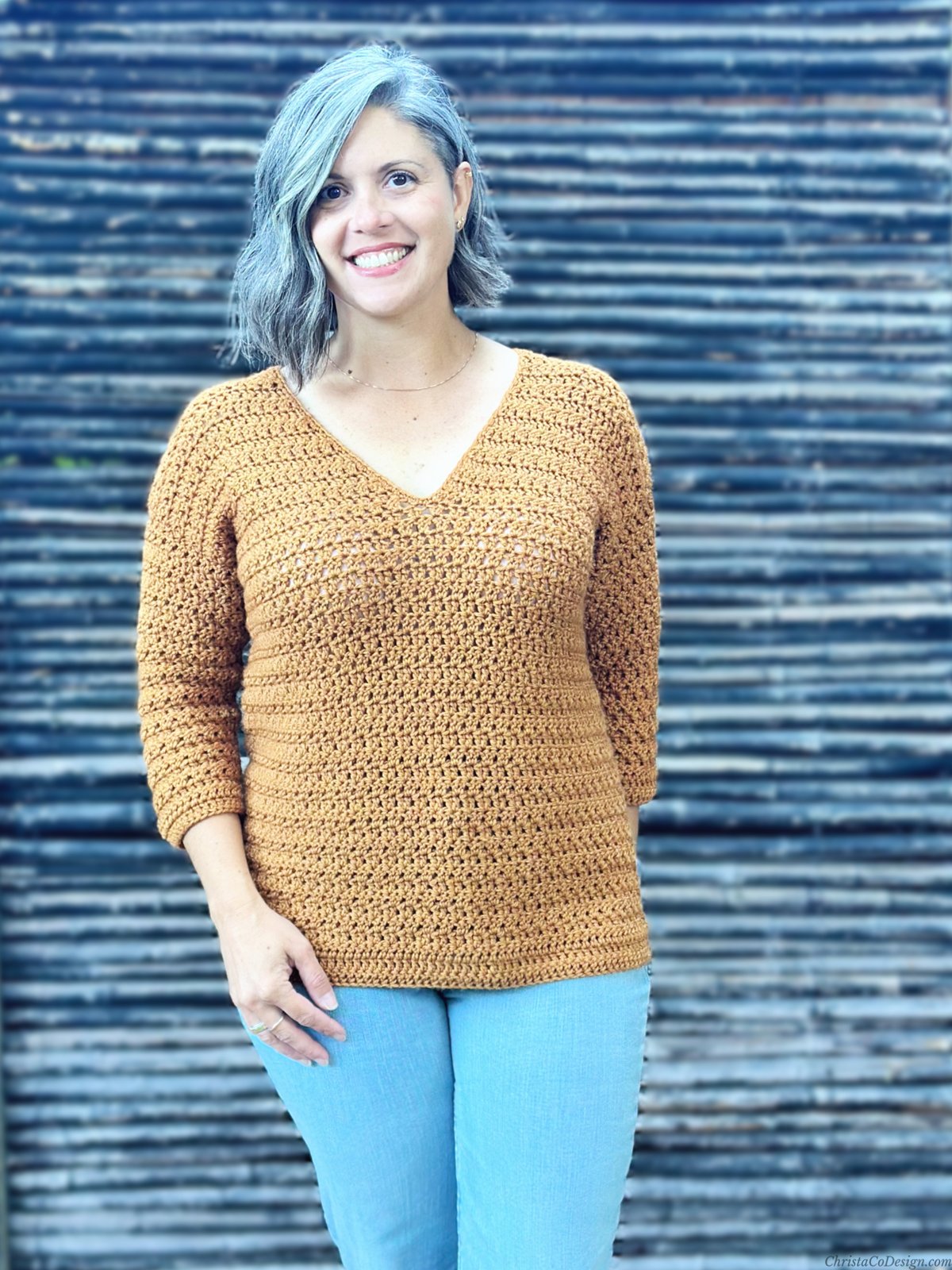 Woman smiling in crochet sweater with v-neck.
