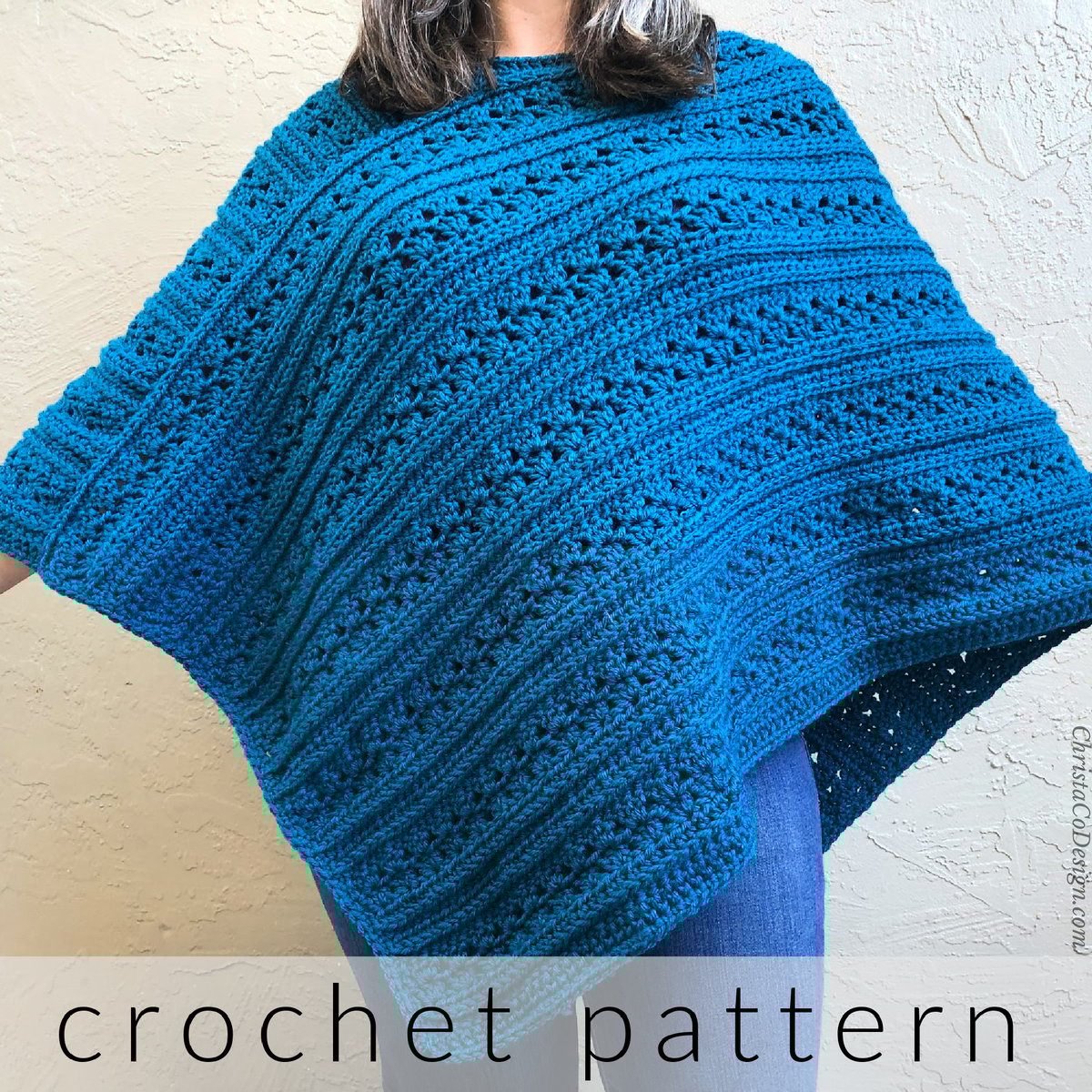 Woman in blue crochet poncho with arms held out.