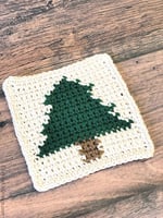 Close up of crochet coaster with Christmas tree in green.
