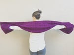 Woman with her arms held out to show pockets of crochet shawl.