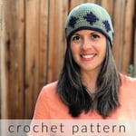 Woman with long dark hair wear green crochet hat with blue diamond pattern.