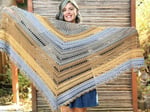 Woman smiling with crochet triangle shawl held wide across front.