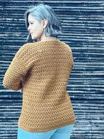 Woman turned to show back of crochet sweater.