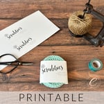 Mint round crochet scrubbies wrapped in paper label surrounded by notions.