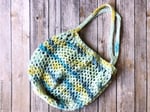 Crochet market tote in blue yellow white on table.