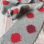 Grey crochet scarf with red circles laid out.