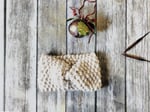 Knit earwarmer with bell and needles.