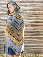 Woman wrapped in crochet shawl of textured stitches and fall colors.