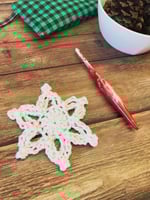 Angled view of crochet snowflake in glitter yarn.