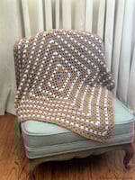 Brown, purple and white granny rectangle blanket draped to show center.