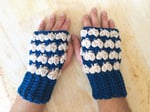 Mens hands laid flat on table in blue and cream crocheted fingerless gloves.