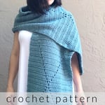 Woman in white dress blue crochet shawl with diamond pattern draped on shoulder.