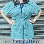 Woman with hands on hips wear crochet cardigan in sage with belted tie in front.