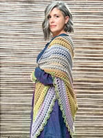 Side view of woman in delicate crochet shawl of grey and golden brown.
