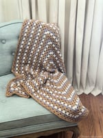 Crochet granny rectangle blanket draped on chair.