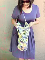 Woman opening crochet mesh bag in white yellow and blue.