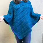 Woman wearing textured blue crochet poncho.