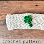 White crochet headband with green 4 leaf clover sewn on.