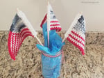 3 crochet us flags in mason jar with blue tissue paper.