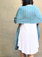 Woman in white dress with blue crochet shawl wrapped across back to show diamond design.