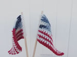 Two small crochet flags on dowels waving.