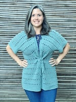 Woman smiling in crochet cardigan with short sleeves.
