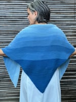 Woman with blue ombre knit shawl draped over back.