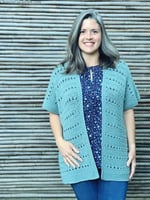 Woman in green crochet cardigan with loose open fit.