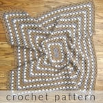 Rectangle granny blanket in purple brown and white on floor.