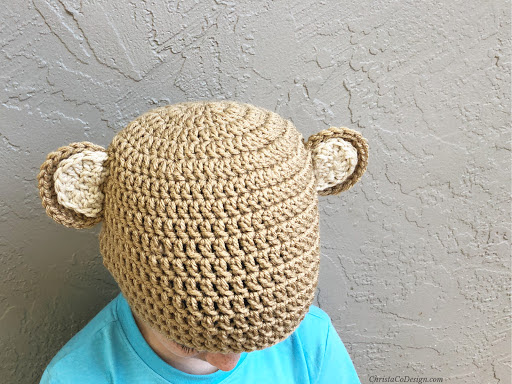 Little boy with crochet bear hat on.