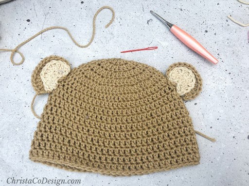 Needle, hook and crochet ears ready on hat.