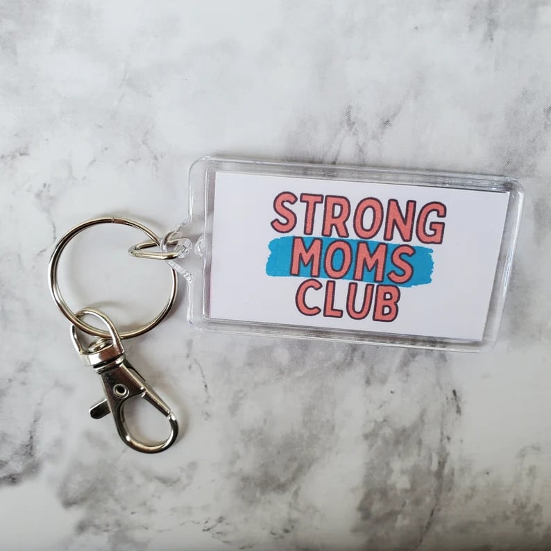 acrylic keychain with white background and words strong moms club, marble background